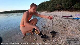 A pretty woman performs nude fire dancing on the beach at sunset.